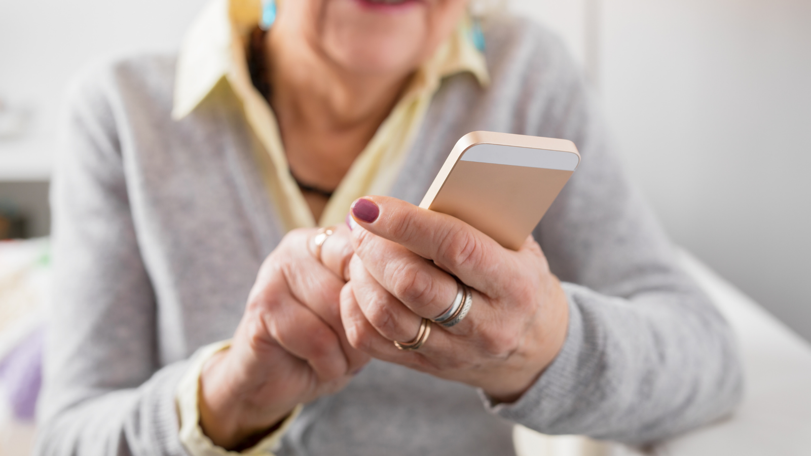 Ältere Frau tippt auf ihr Handy, um Text aus einem Foto zu kopieren