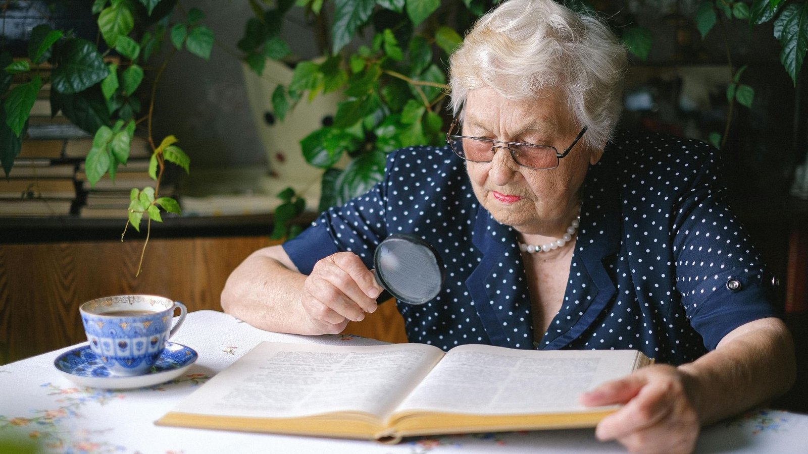 Seniorin nutzt Lupe zum Lesen eines alten Buchs
