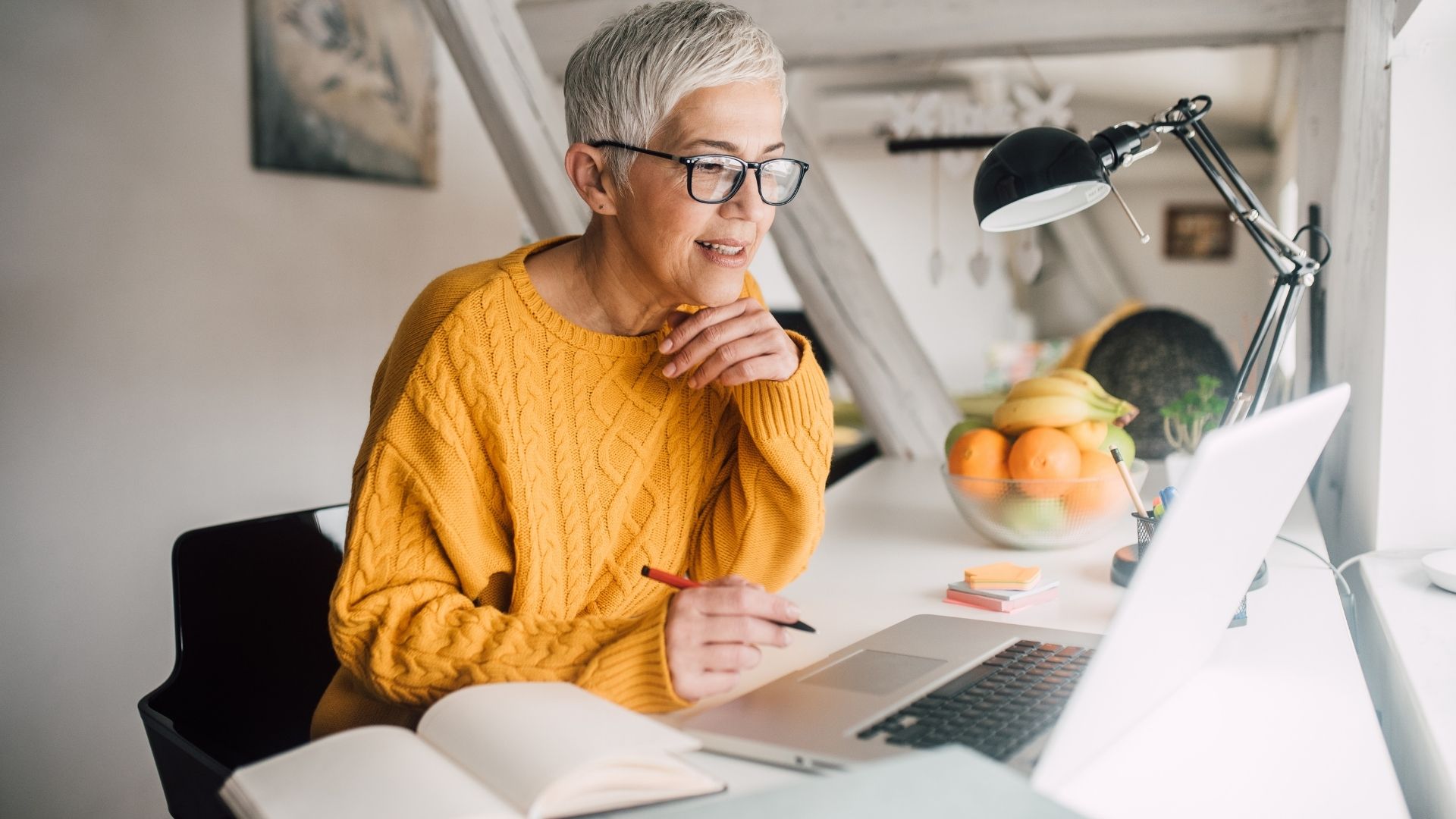 eine ältere Dame sitzt lernend vor ihrem Computer