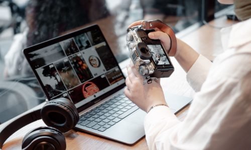 digitale Fotos Notbook mit Bildern, davor ein Mensch mit Kamera