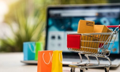 online shopping Einkaufswagen mit vielen Tüten vor einem Notebook
